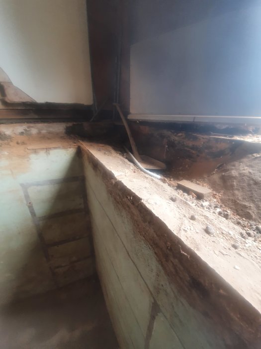 Rivet bjälklag i ett gammalt torp som visar en källarvägg och springa mellan husvägg och källare.