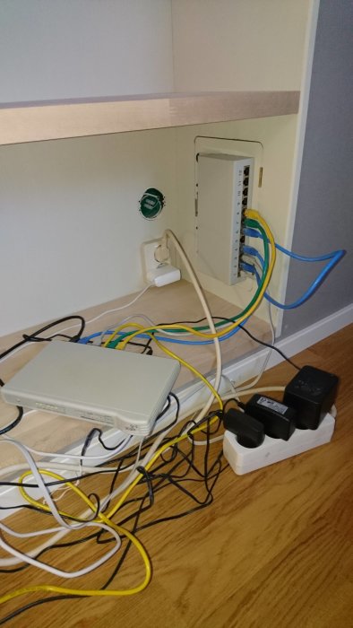 Rörlig nätverksinstallation med patchpanel, switch, och oorganiserade ethernetkablar på golv.