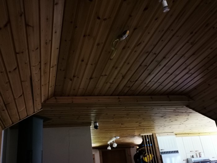 Inredning i ett fritidshus med synliga spår av vattenskador på träpaneltak och väggar som kan behöva renovering.