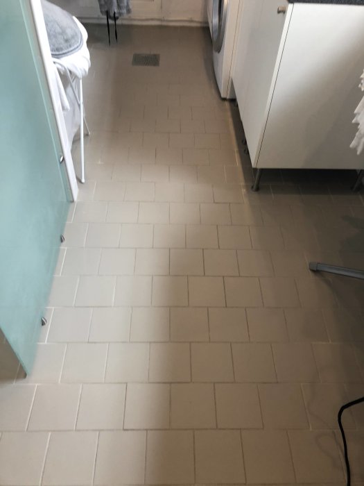 Ett köksgolv i en tvättstuga med kakelplattor där vattenburen golvvärme övervägs för värme och komfort.