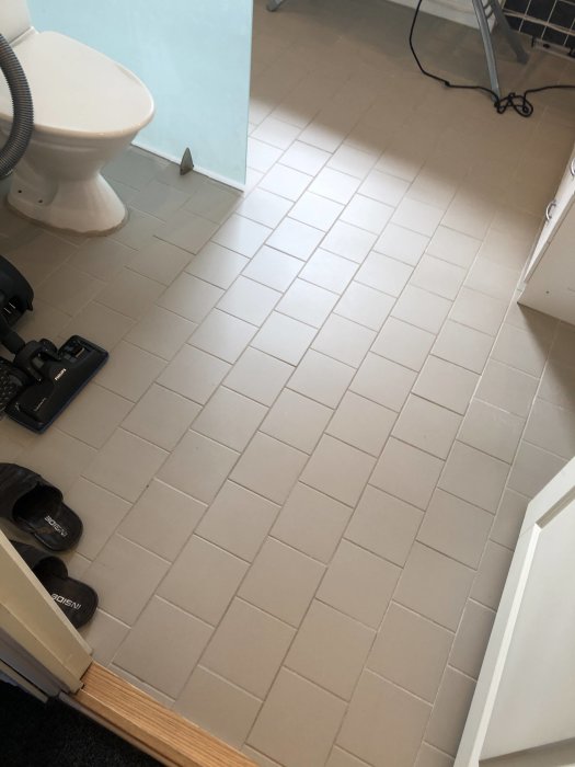 Tvättstugans kalla golvbeläggning som användaren överväger att förse med vattenburen golvvärme.