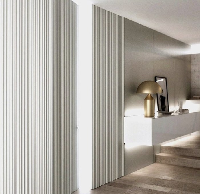 Vågig panelbeklädd dörr i minimalistiskt interiör med spegel och lampa.