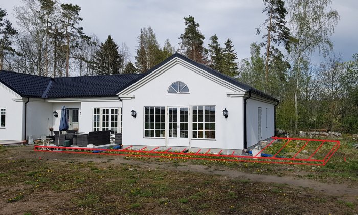 Vit enplansvilla med markerad yta för planerad altanbyggnad i rött och gult.