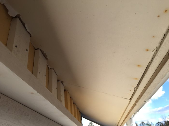 Ljusgrå skiva som tros vara eternit monterad som överhäng på ett hus.