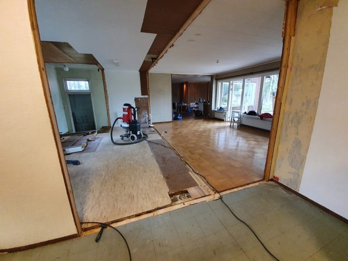Renoveringsprojekt i hem där en gammal källardörr syns längst in till vänster i ett tomt rum.
