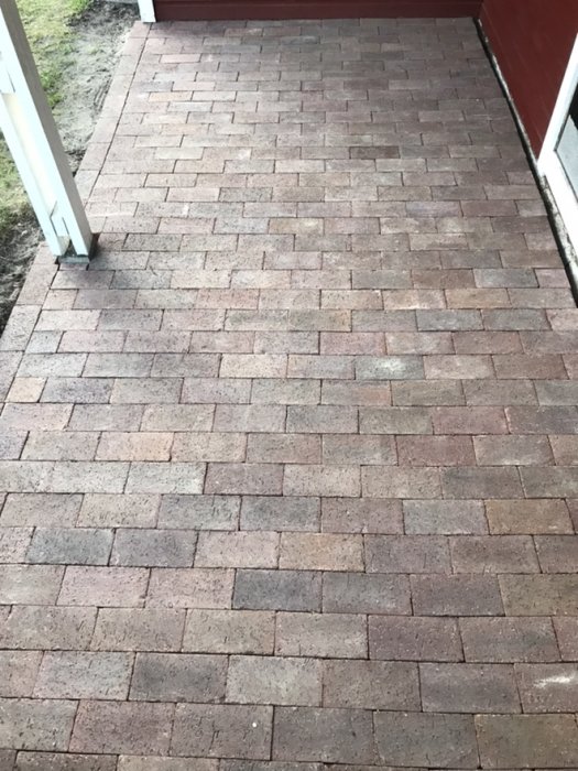 Stenläggning på en uteplats med varierande nyanser av rödbruna markstenar i förband.