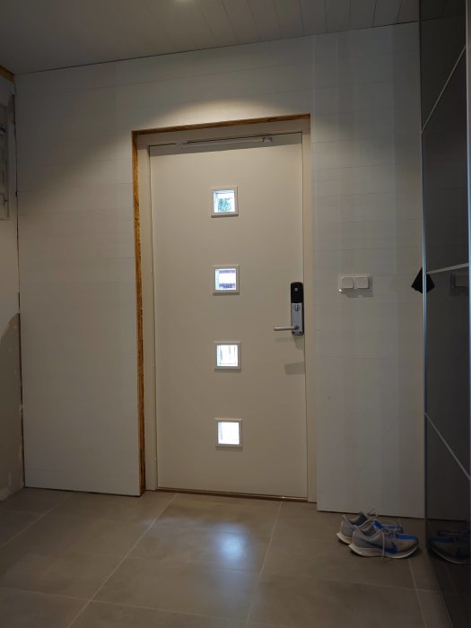 Renoverad vägg utan foder runt en ny ytterdörr i ett hem.