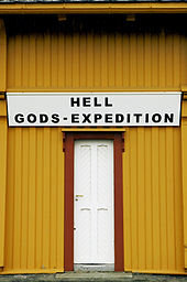 Skylt med texten "HELL GODS-EXPEDITION" över en dörr på en gul byggnad.