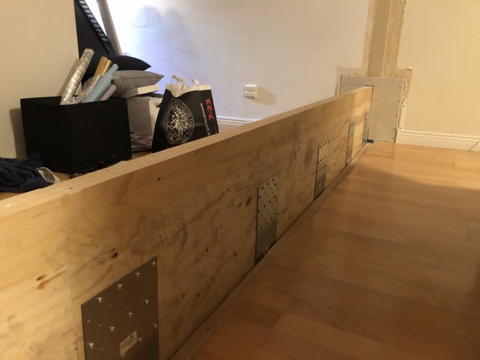 A Kerto beam installed in a room, with metal plates affixed to it, lying on a wooden floor beside construction materials.
