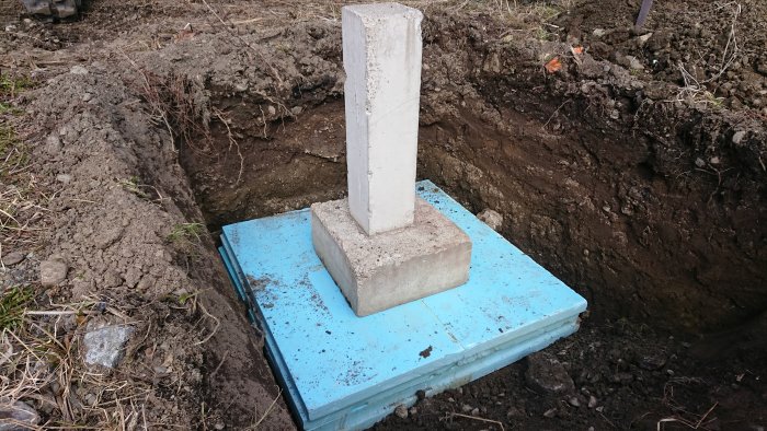 Nyinstallerad betongplint på blå isolerplatta i utgrävd mark.