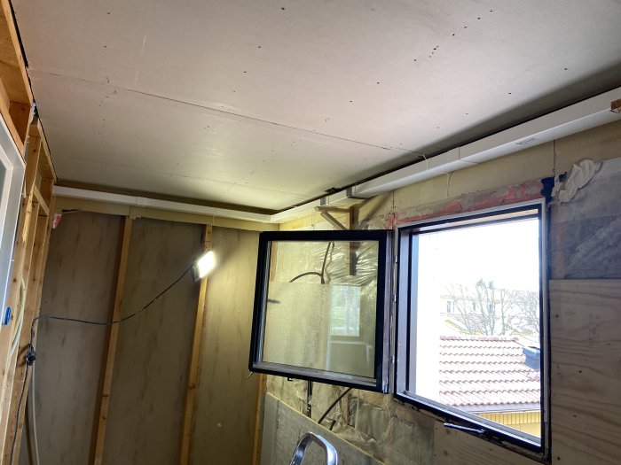 Renoveringsarbete med installation av ventilation i ett rum med nakna träväggar och isolering.