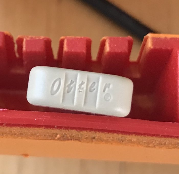 Komponent med texten "Otter" på röd plastbas i elektronisk apparat.