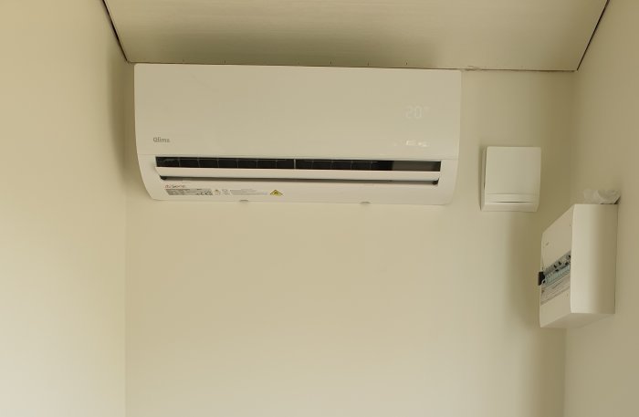 Clima SC-JA2519 luftvärmepump monterad på vägg visar 20 grader, bredvid termostat och internetmodul.