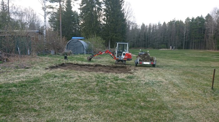 Grävmaskin gräver ett potatisland på en lummig tomt med ett tält, presenning och skog i bakgrunden.