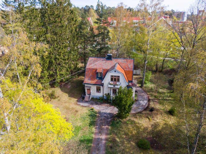 Luftvy av ett traditionellt rött hus med vita knutar och stort trädgård i Tors Backe.