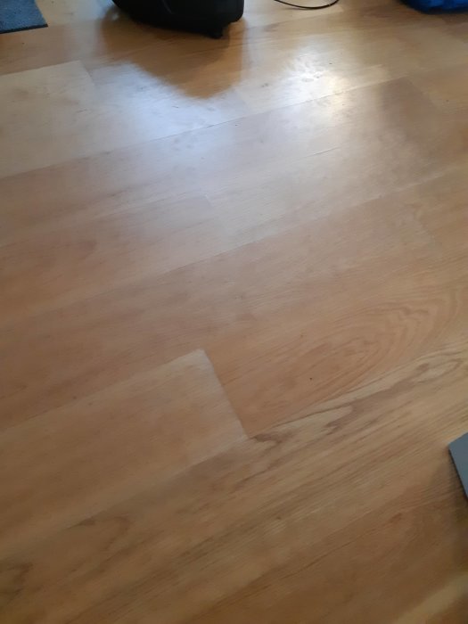 Parkettgolv med ojämn glans och tydliga moppningsspår och fotavtryck.