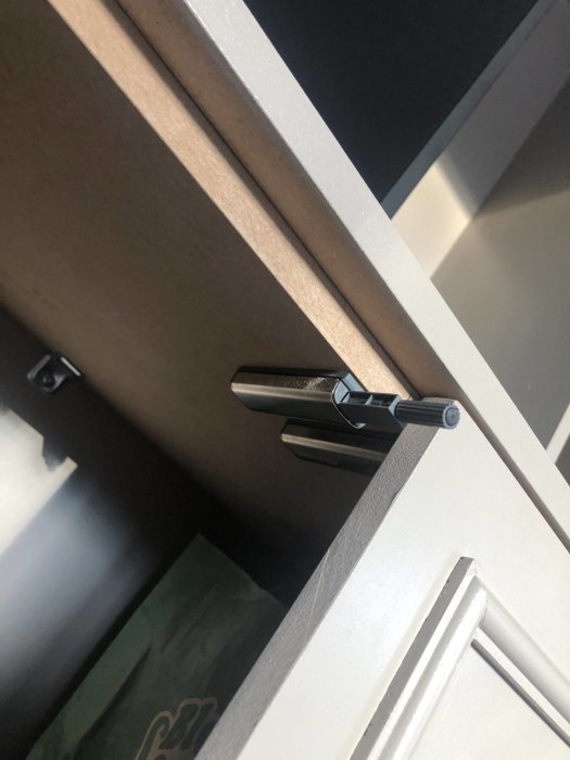 Närbild på välmonterat köksskåpsgångjärn mellan dörr och skåpsstomme.