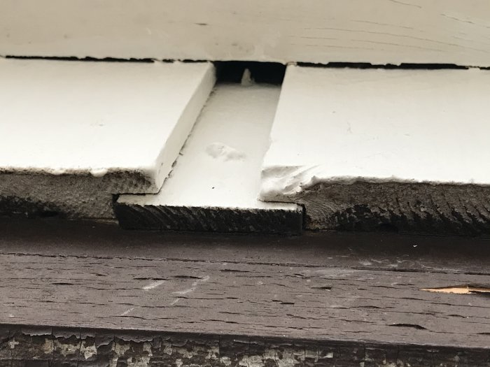Närbild på en vitmålad träpanel med en överlappningsteknik på ett garage.