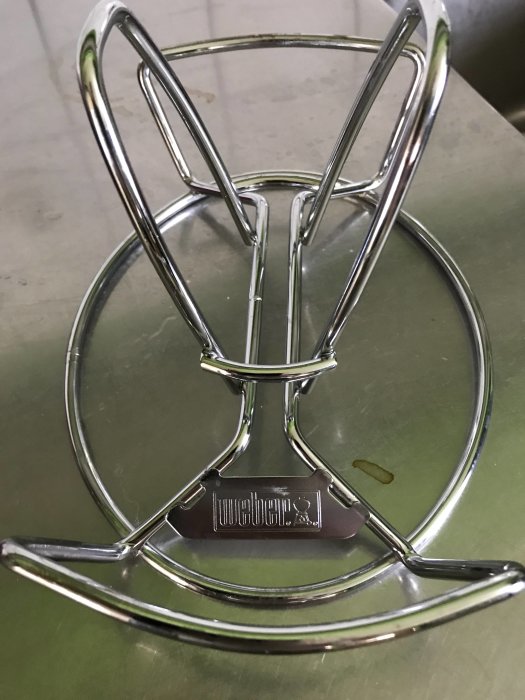 Chrome-finish Weber grill basket on a shiny surface, showcasing the Weber logo.