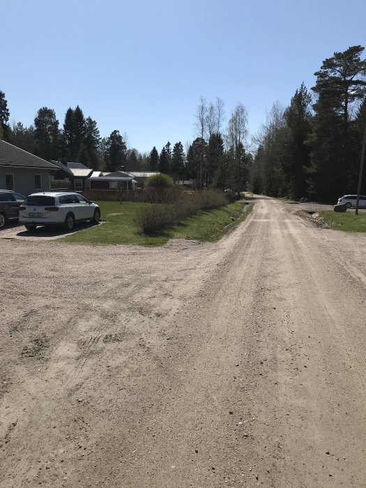 Grusväg med parkerade bilar och träd vid sidan, potentiell plats för mötesplats på 7x40 meter.