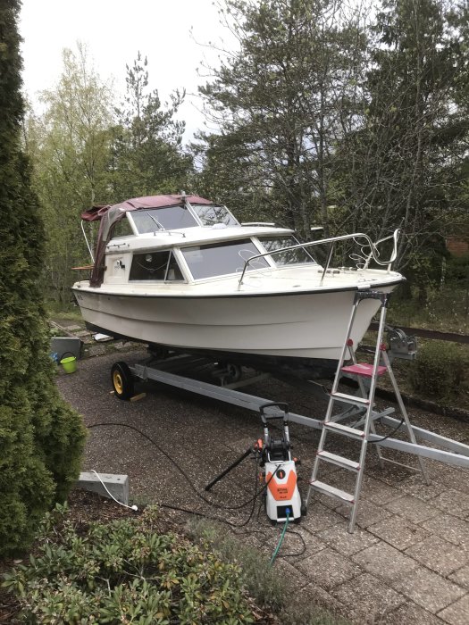 Fjord 21-fots båt på trailer vid hemmet med stege och högtryckstvätt i förgrunden.