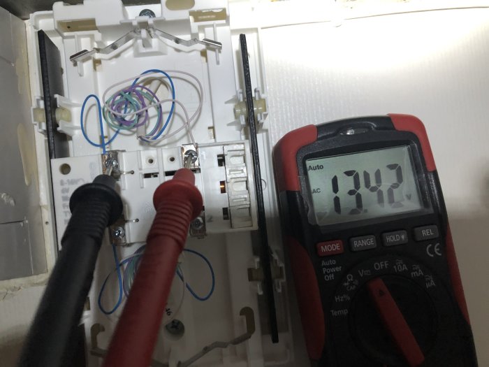 Multimeter visar 13,4V på ringklockans anslutning med kablar och skruvklämmor i bakgrunden.