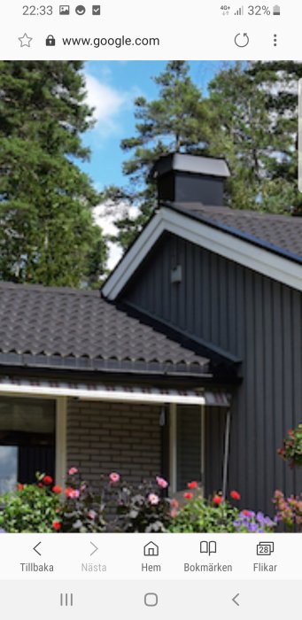 Ett hus med svart plåttak, skorsten och mörk panel som exempel för tillbyggnadsprojekt.