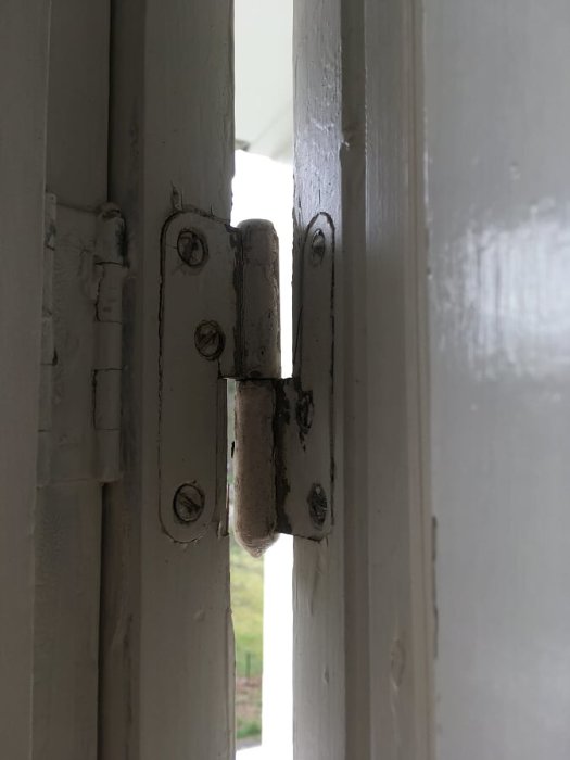Sneda övre gångjärn på en balkongdörr som visar större mellanrum uppåt.