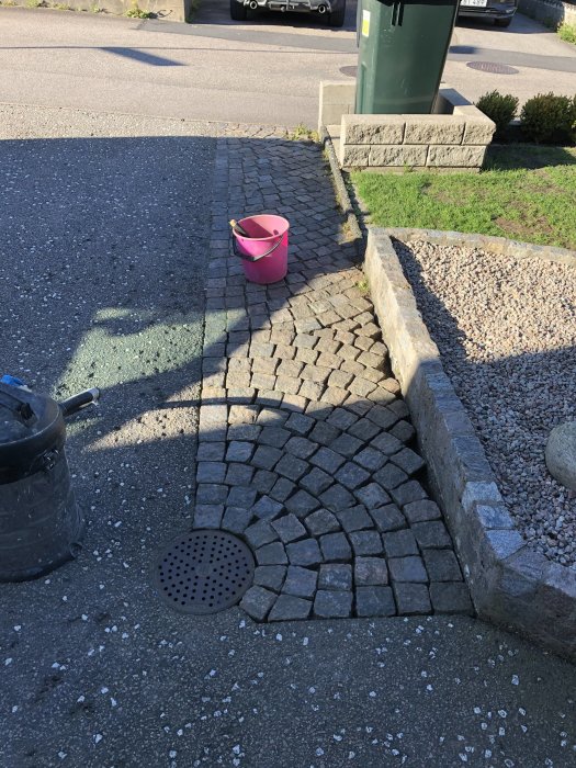 Rensade stenfogar på trottoar med skruvmejsel bredvid en grovdammsugare och rosa hink.