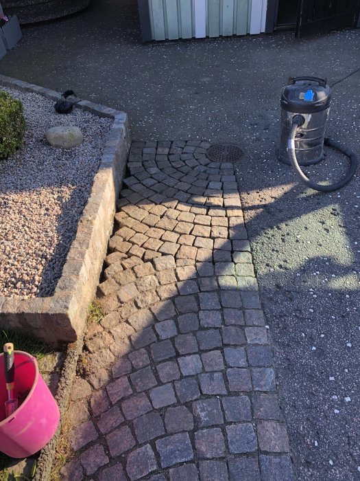 Rensning av fogar på stenläggning med skruvmejsel och dammsugare vid uppfart.