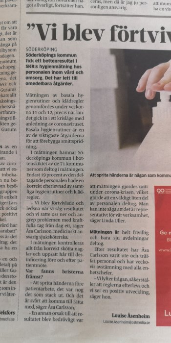 Del av en tidningsartikel om Söderköpings kommuns hygienrutiner med en person som pekar på texten.