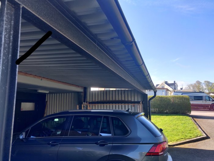 En carport med metalltak som visar dess uppbyggnad och tjocklek, utan mittstolpe, med en bil parkerad under.