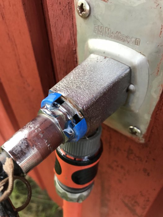 Utomhuskran med läckande blå ring där trädgårdsslang är ansluten.