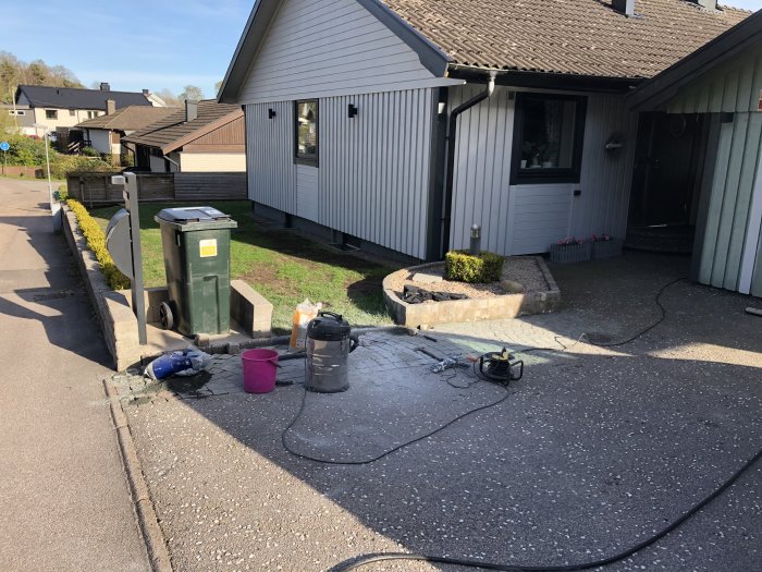 Renoverad gatsten framför hus med verktyg och stenar i varierande färger på uppfart.