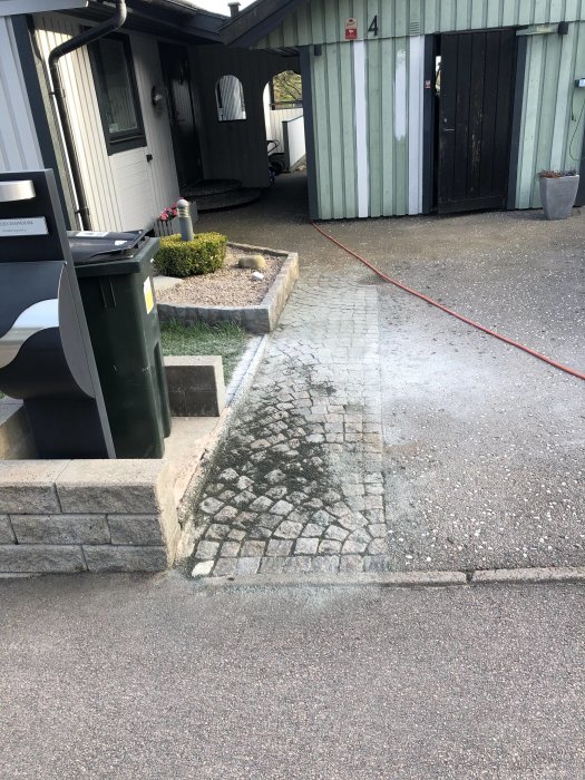 Rensad gatsten framför ett hus med några stenar i avvikande färger insatta i mönstret.