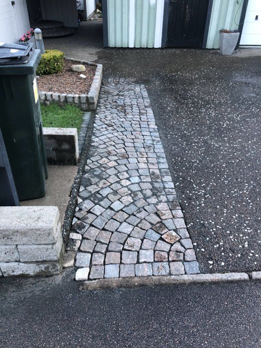 Renoverad gatsten på en uppfart med lagad del i avvikande färger och renad från ogräs.