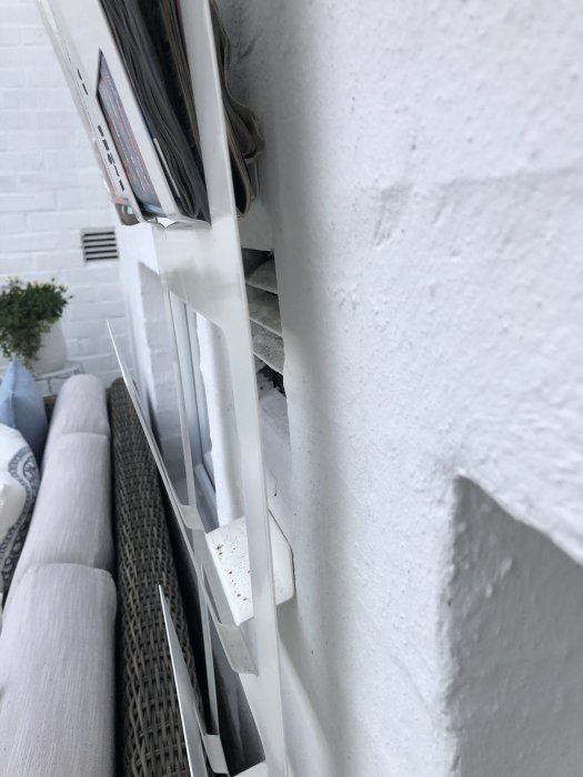 Två tilluftsgaller på en vit vägg i ett uterum som är oisolerat, intill en soffa och dynor.