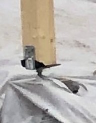 Limträstolpe monterad på justerbar stolpsko och betongplint, med syllpapp runt plinten för avrinning.