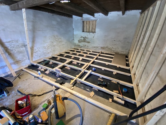 Installation av golvreglar i ett pågående renoveringsprojekt i ett rum med nakna väggar.