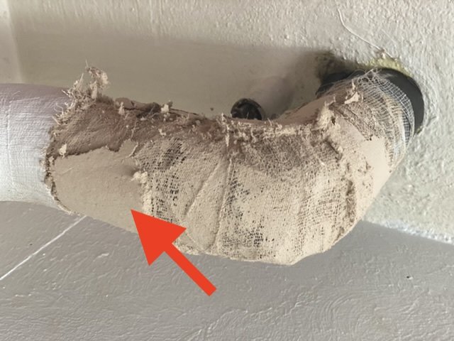 Rörisolering med sliten yta som indikerar möjlig asbest, med röd pil pekande på materialet.