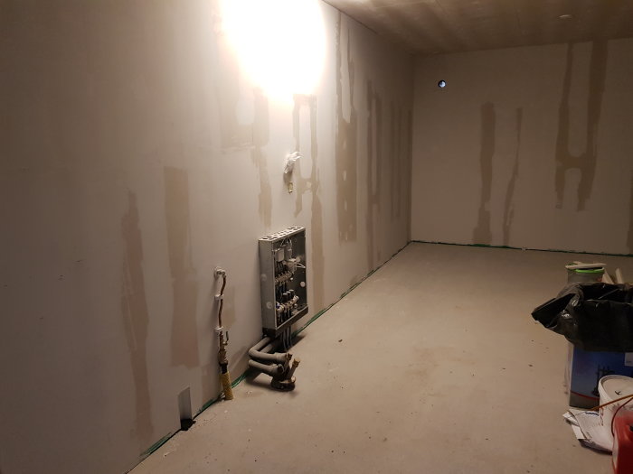 Halvfärdig vägg redo för renovering med synlig spackling och elektrisk kopplingsdosa.