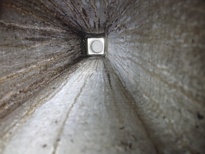 Inuti en vertikal kanal eller rör med synlig längd och ljusöppning i änden.