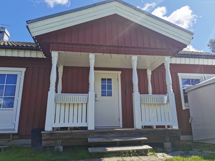 Rödfärgad farstukvist med vita pelare och en vit dörr i ett bostadshus planeras byggas in för hall och toalett.