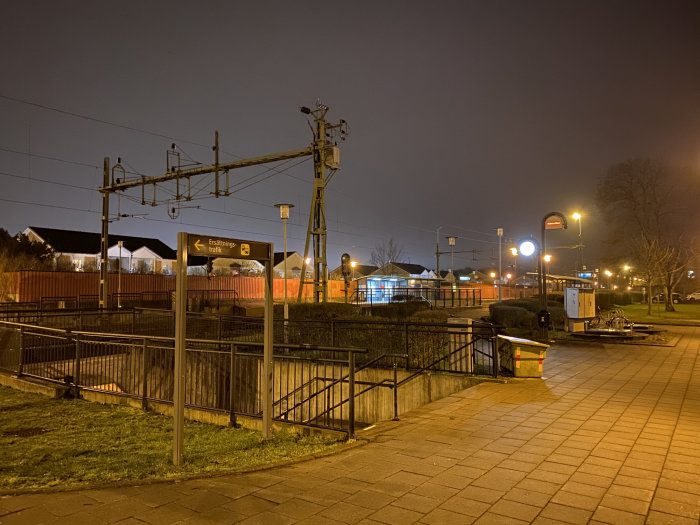 Kvällsbild av en järnvägsstation med belysning och skylt för ersättningstrafik, känsla av ödslighet.