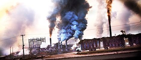 Fabrik i Brasilien som släpper ut tjock rök, symboliserar miljöpåverkan från etanoltillverkning.