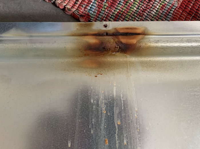 Brända och läckande rester vid övre värmeelementet i en ugn.