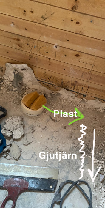 Renoveringsplats med synliga plaströr och notering om gjutjärnsrör, omgivet av byggmaterial och verktyg.