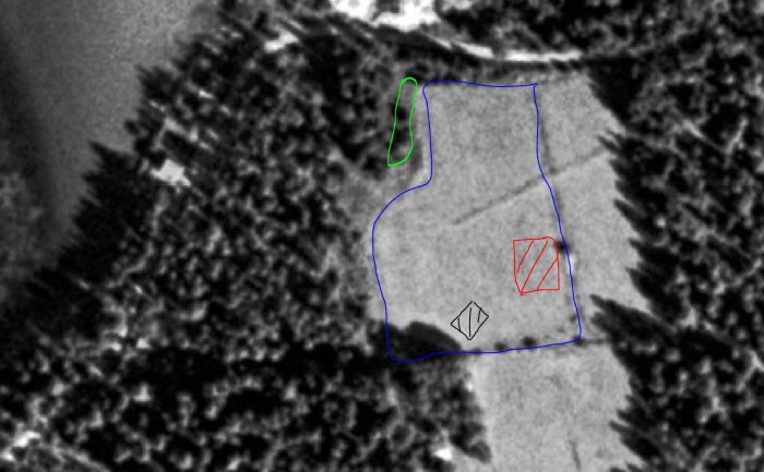 Svartvit flygbild av mark med markeringar; blå linjer för diken, röd för planerad stuga.