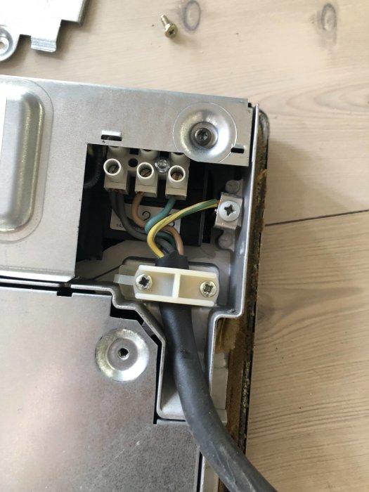 Bild på öppen installation av induktionshäll med synliga trådar och en 3-fas kabel inkopplad.