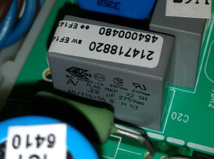 En kondensator monterad på ett grönt kretskort, med detaljerade specifikationer tydligt synliga.